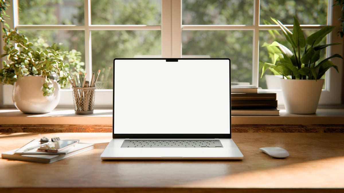 Laptop on a desk showing a website design in a bright workspace